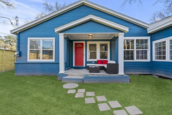 A blue house with a red door, a porch with outdoor furniture, and a stone pathway leading to the door. - The Retreat- Family Funhouse w/Waterfront Access! (Highlands)