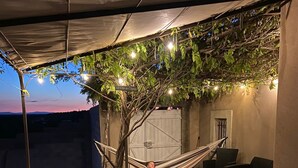 An outdoor patio with a hammock, black wicker furniture, a grill, and string lights. - Magnificent villa Chloéline: Swimming pool and superb view (Pougnadoresse)