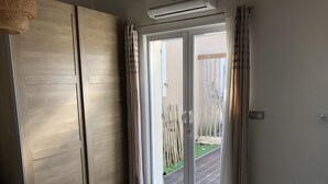 A room with a sliding door leading to a balcony, wooden flooring, and a ceiling-mounted air conditioning unit. - Magnificent villa Chloéline: Swimming pool and superb view (Pougnadoresse)