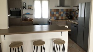 A modern kitchen with a central island, bar stools, a dishwasher, and a refrigerator. - Magnificent villa Chloéline: Swimming pool and superb view (Pougnadoresse)