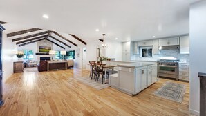 A spacious kitchen with a large island, wooden flooring, and modern appliances.