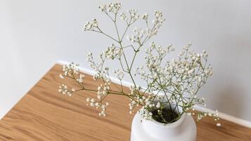 Un vase blanc orné de petites fleurs de gypsophile, posé sur une table en bois.