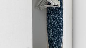 A closet with hanging clothes and folded towels.