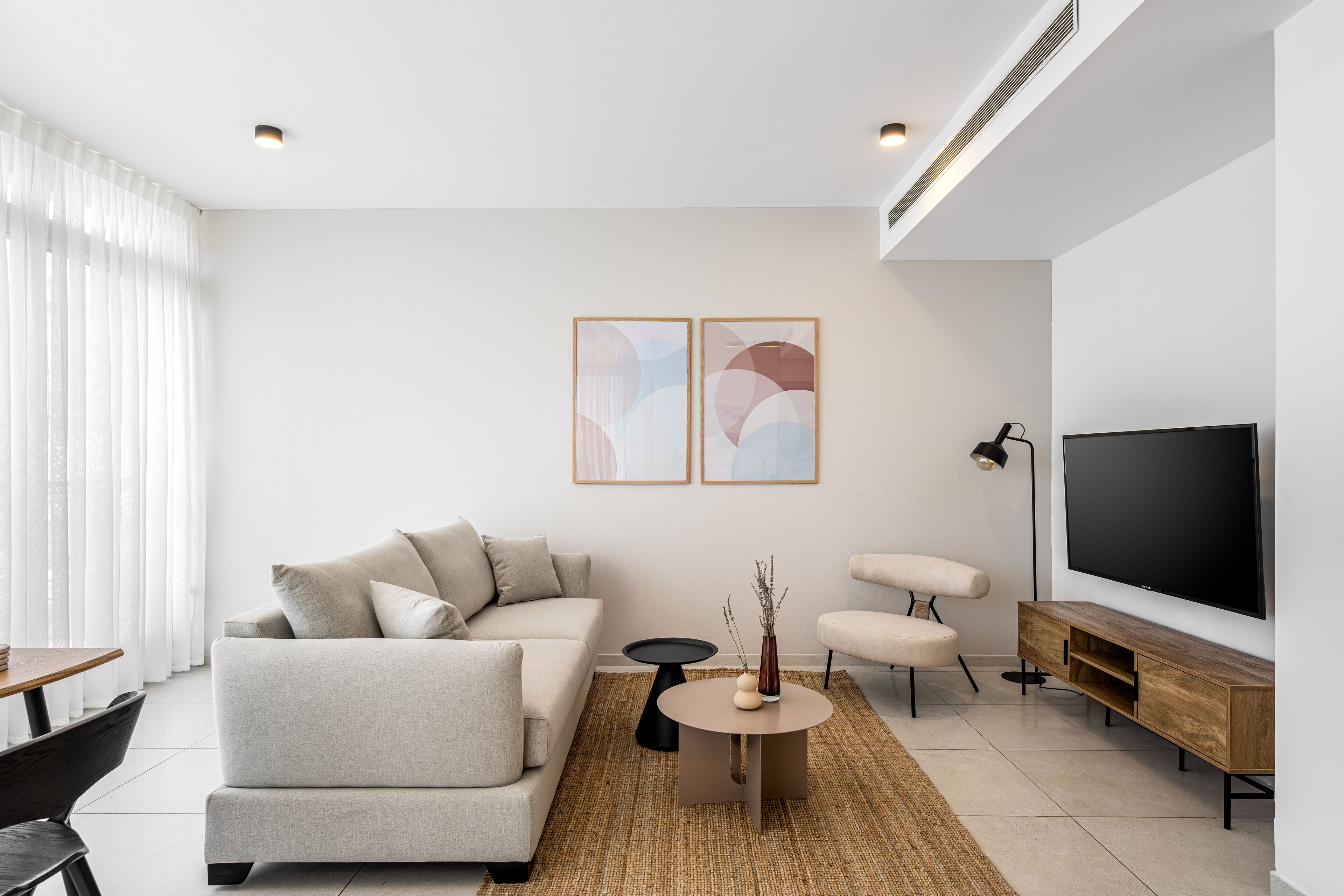 A modern living room with a sofa, armchairs, a coffee table, and a TV.
