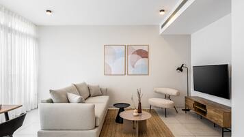 A modern living room with a sofa, armchairs, a coffee table, and a TV.