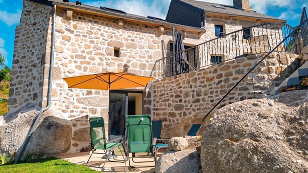 A stone building with a balcony, outdoor seating, and a staircase. - Lou Vachou - Rimeize (RIMEIZE)