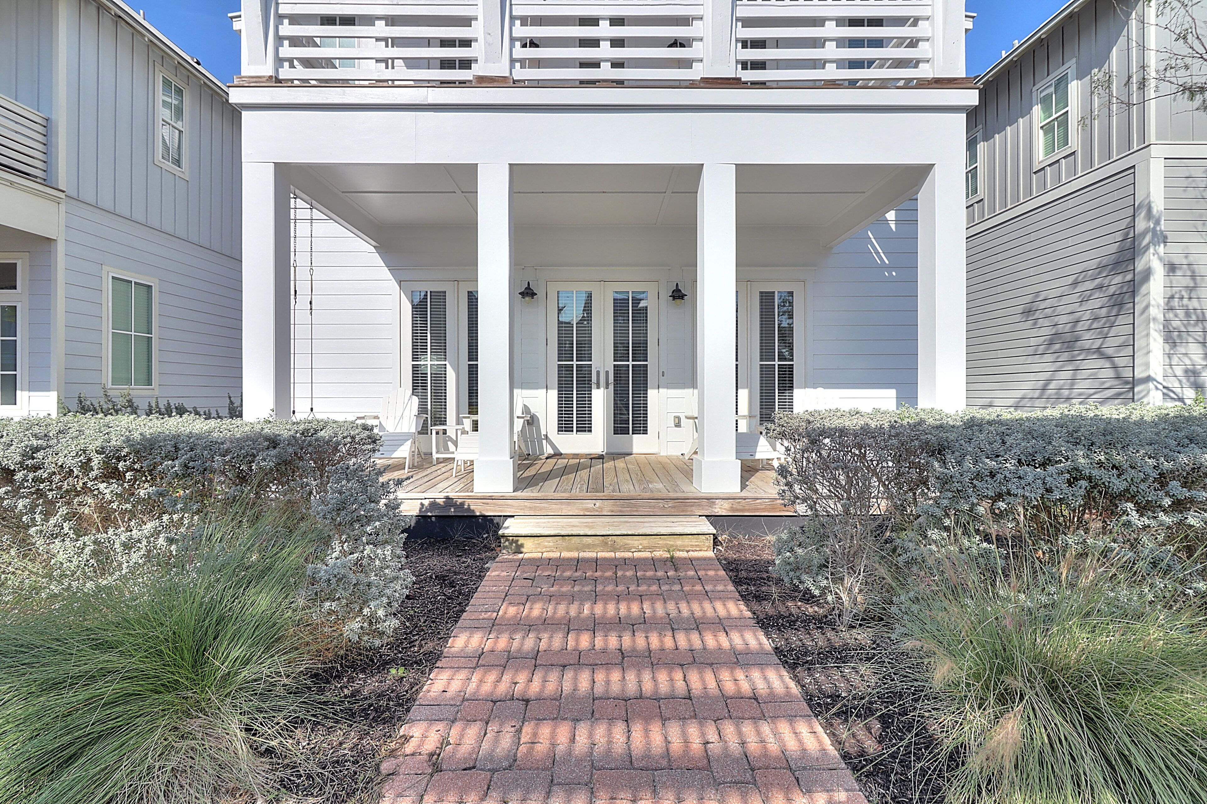A two-story house with a covered porch, a brick pathway leading to the entrance, and a well-maintained garden.