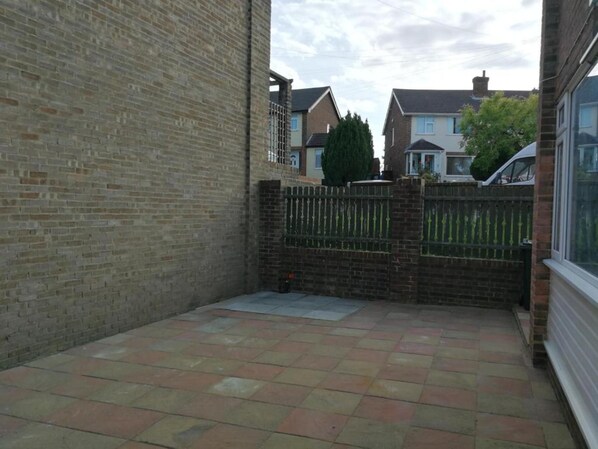 A courtyard with a brick wall, a metal gate, and a tiled floor.