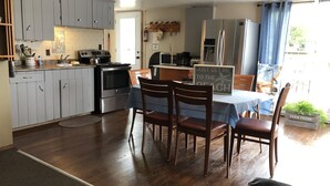 Uma cozinha com armários cinza, um fogão e um espaço de jantar com mesa e cadeiras.