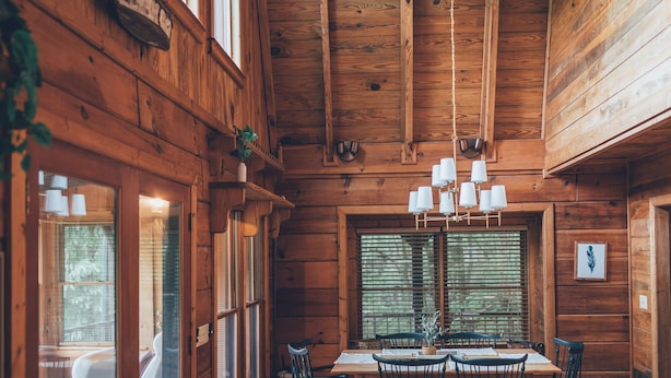 Een houten cabin met een eethoek, een plafondventilator en een groot raam.