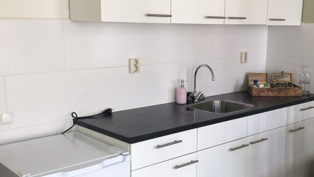 Eine moderne Küche mit weißen Schränken, einer schwarzen Arbeitsplatte und einem eingebauten Geschirrspüler.