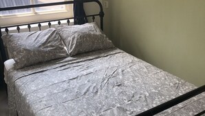 Ein Einzelbett mit einem gemusterten Bettbezug und einem schwarzen Metallgestell.