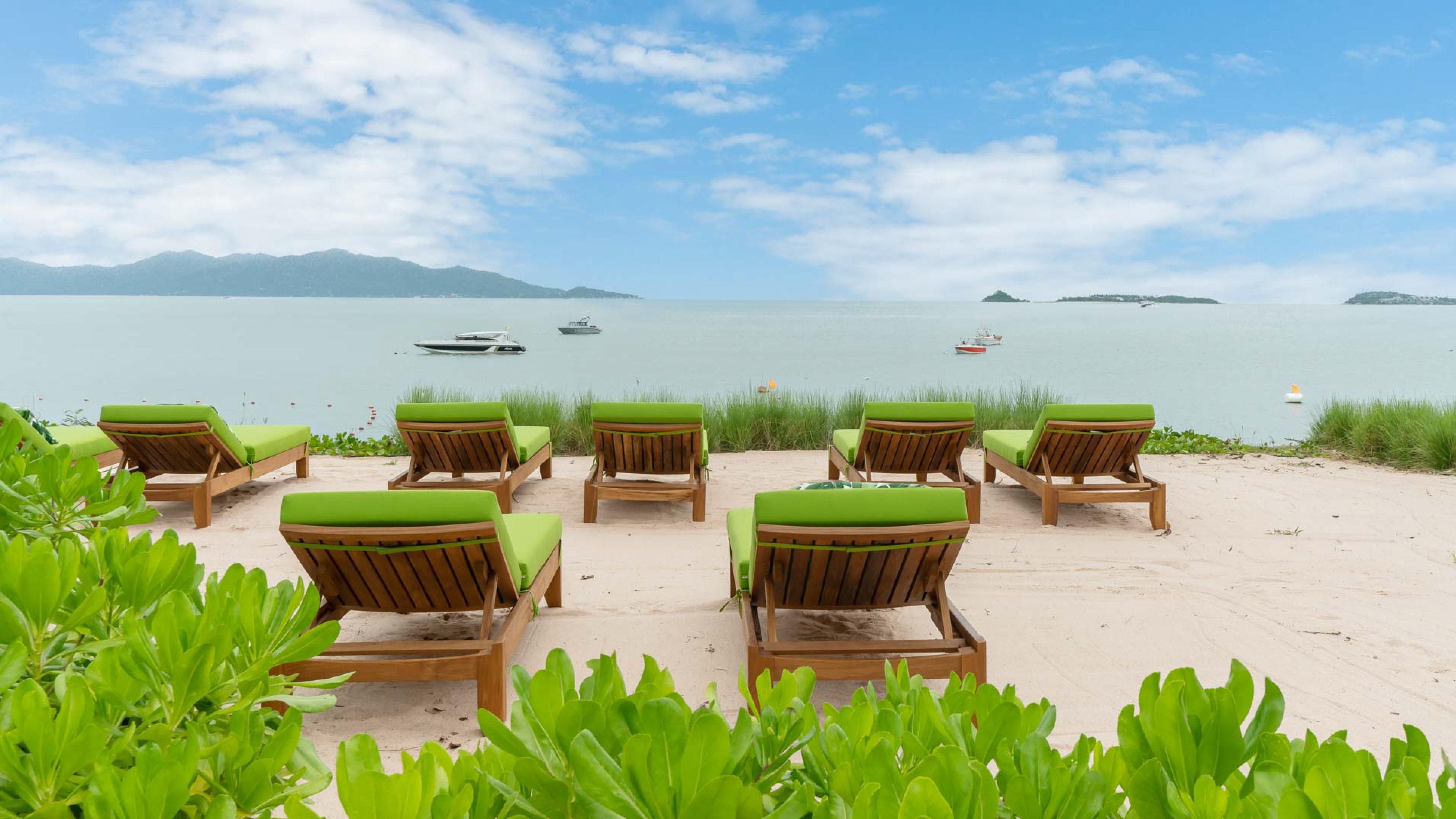 Una playa con sillones de madera y vistas al mar.