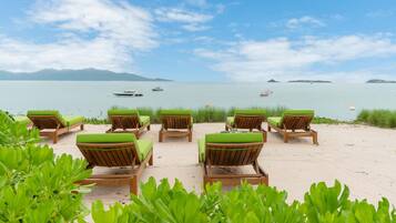 Una playa con sillones de madera y vistas al mar.
