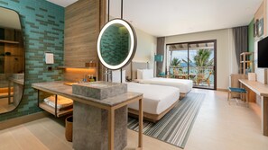 Habitación de hotel con una cama grande, una zona de estar con una mesa y sillas, un baño con tocador y un balcón con vistas.