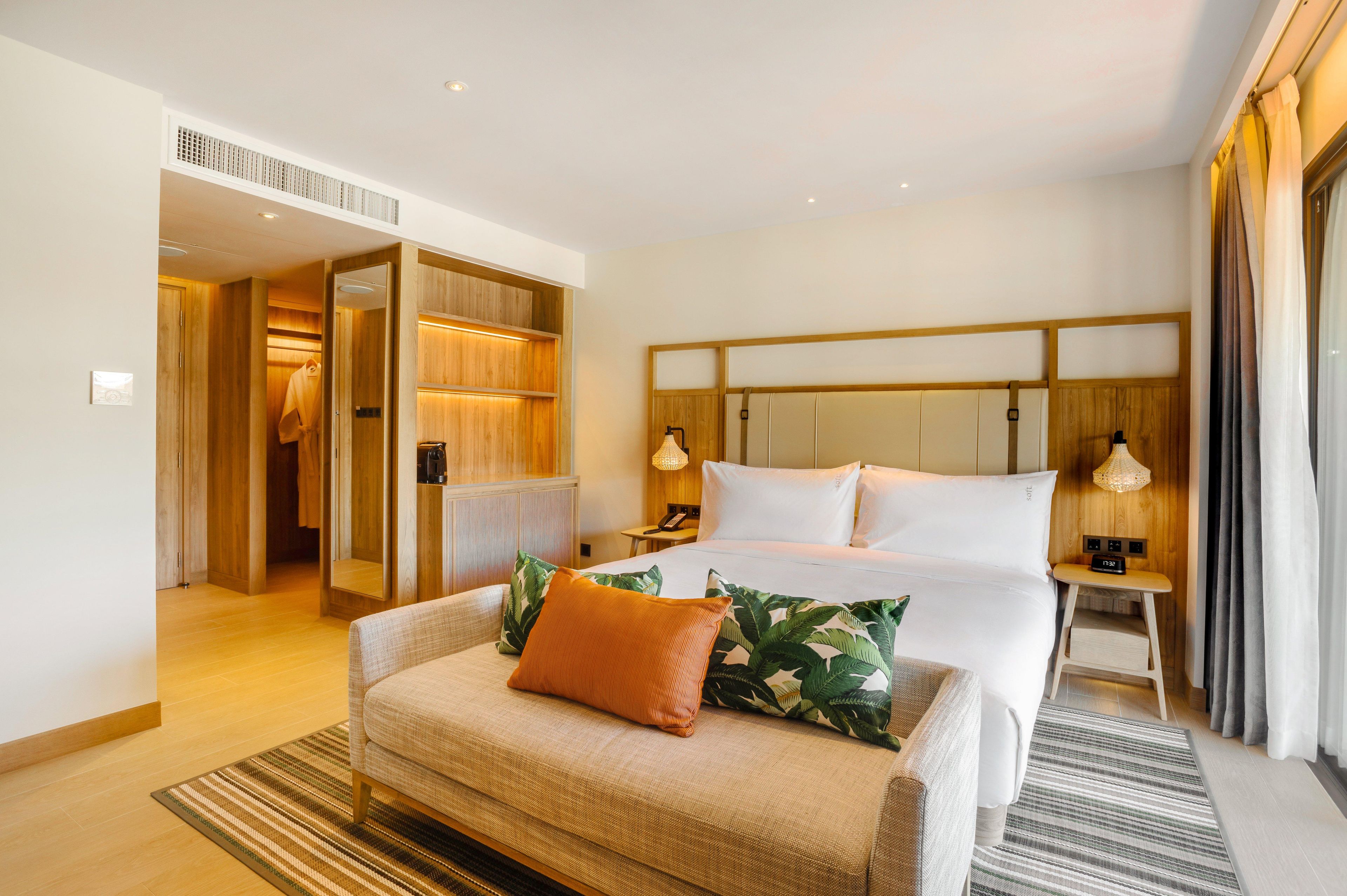 Una habitación de hotel con cama, sofá, mesita de noche y vestidor.
