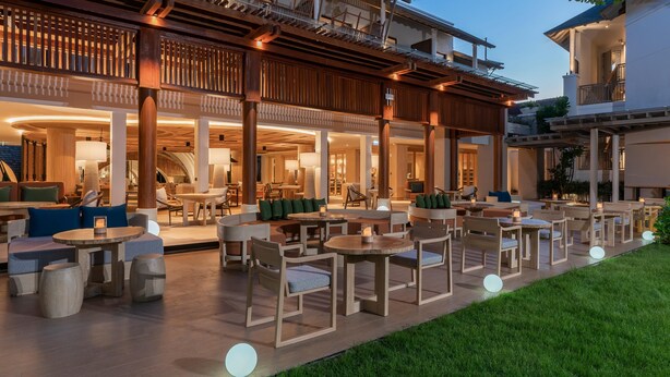 An outdoor seating area with tables and chairs, a covered patio, and a view of the interior. - Holiday Inn Resort Samui Bophut Beach (Koh Samui)