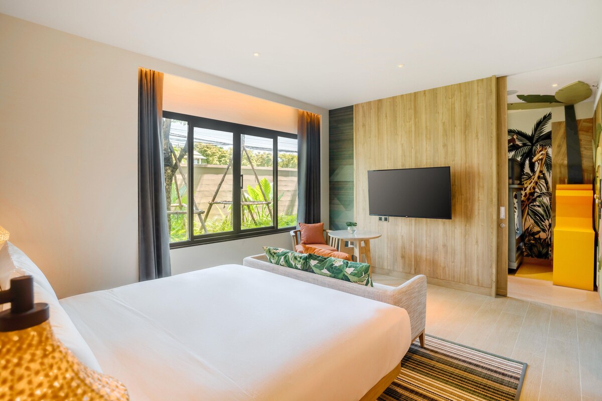 Une chambre d’hôtel avec un lit, une télévision, une petite table et une vue sur la verdure.