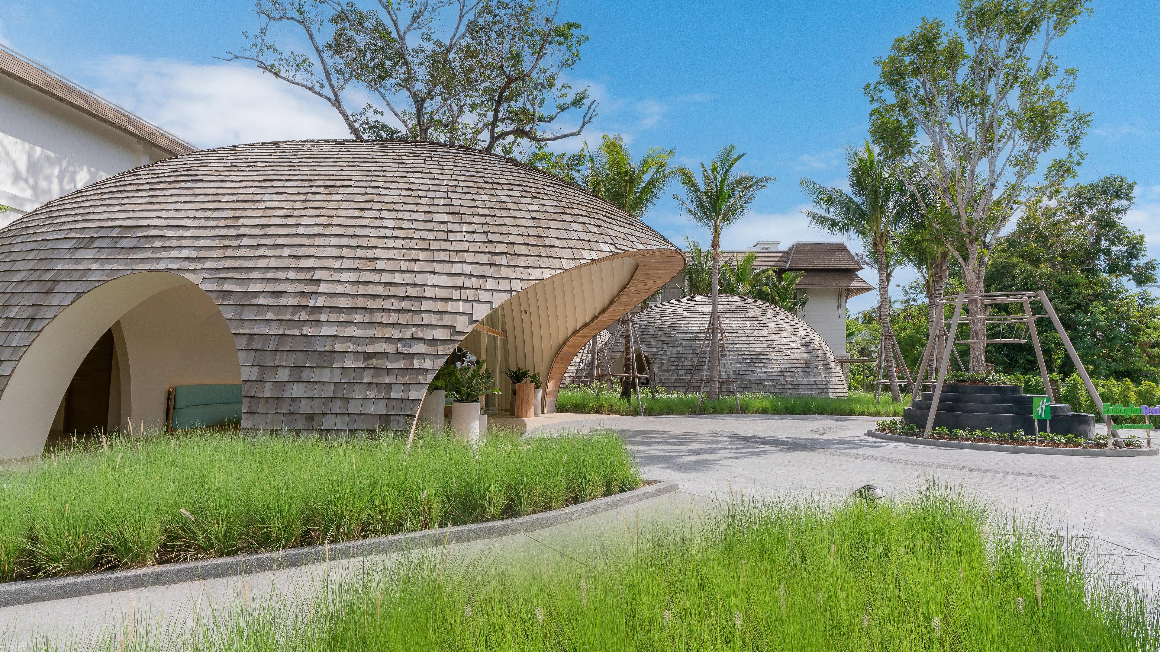 Un edificio moderno con un diseño esférico distintivo, rodeado de exuberante vegetación y palmeras.