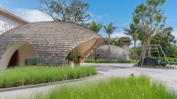Un edificio moderno con un diseño esférico distintivo, rodeado de exuberante vegetación y palmeras.
