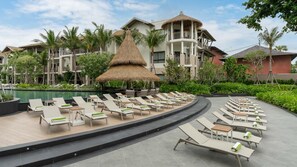 A resort with a pool area featuring sun loungers and a thatched-roof structure. - Holiday Inn Resort Samui Bophut Beach (Koh Samui)