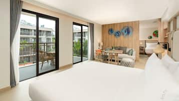 Una habitación de hotel con una cama grande, un balcón con mobiliario exterior, una pared de acento de madera y un comedor.