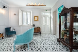 Classic design features a geometric patterned floor, a dresser with glass doors, and a chandelier.