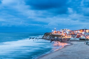 Un pueblo costero con edificios a lo largo del acantilado, un faro y una playa.