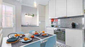 A modern kitchen with white cabinets, a coffee machine, and a dining area with a table set for breakfast. - ♥ Unique & Stylish Historic House ♥ Great Location ♥ Close to Gardens & River (Leiria)