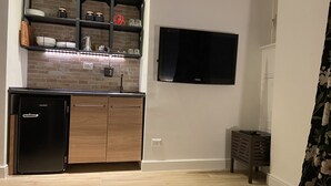 Una cocina moderna con refrigerador empotrado, armarios de madera, salpicadero de ladrillo y televisor de pantalla plana montado en la pared.