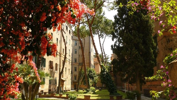 Un patio con un camino empedrado, rodeado de edificios con múltiples ventanas y balcones.