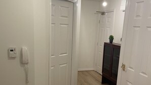 Un pasillo con puertas blancas, suelo de madera y un teléfono en la pared.