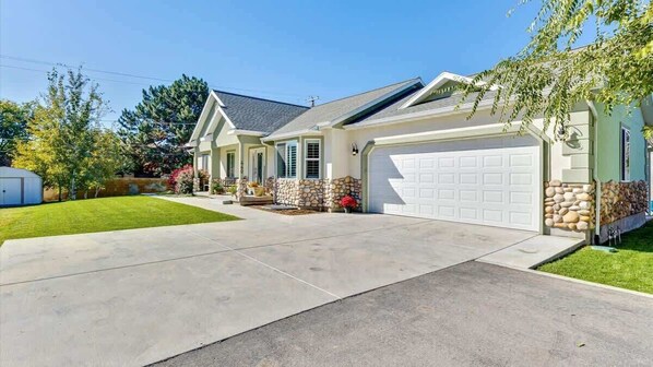 A single-story house with a garage, a stone accent wall, and a well-maintained lawn.
