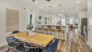 Eine geräumige Küche mit einem Holztisch und Stühlen, einer Kochinsel und einem Deckenventilator.