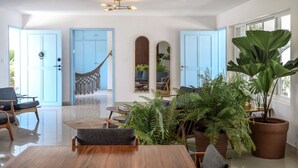 A spacious living room with a large wooden table, comfortable seating, and abundant indoor plants. - Private Oceanfront Villa / Fully Staffed / daily cleaning and concierge. (San Miguel de Cozumel)