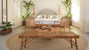 A modern bedroom with a large bed, two wicker chairs, a round wooden table, and potted plants. - Private Oceanfront Villa / Fully Staffed / daily cleaning and concierge. (San Miguel de Cozumel)