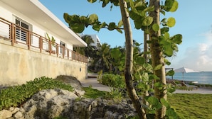 A modern building with a white facade, a balcony with a wooden railing, and a view of the ocean. - Private Oceanfront Villa / Fully Staffed / daily cleaning and concierge. (San Miguel de Cozumel)