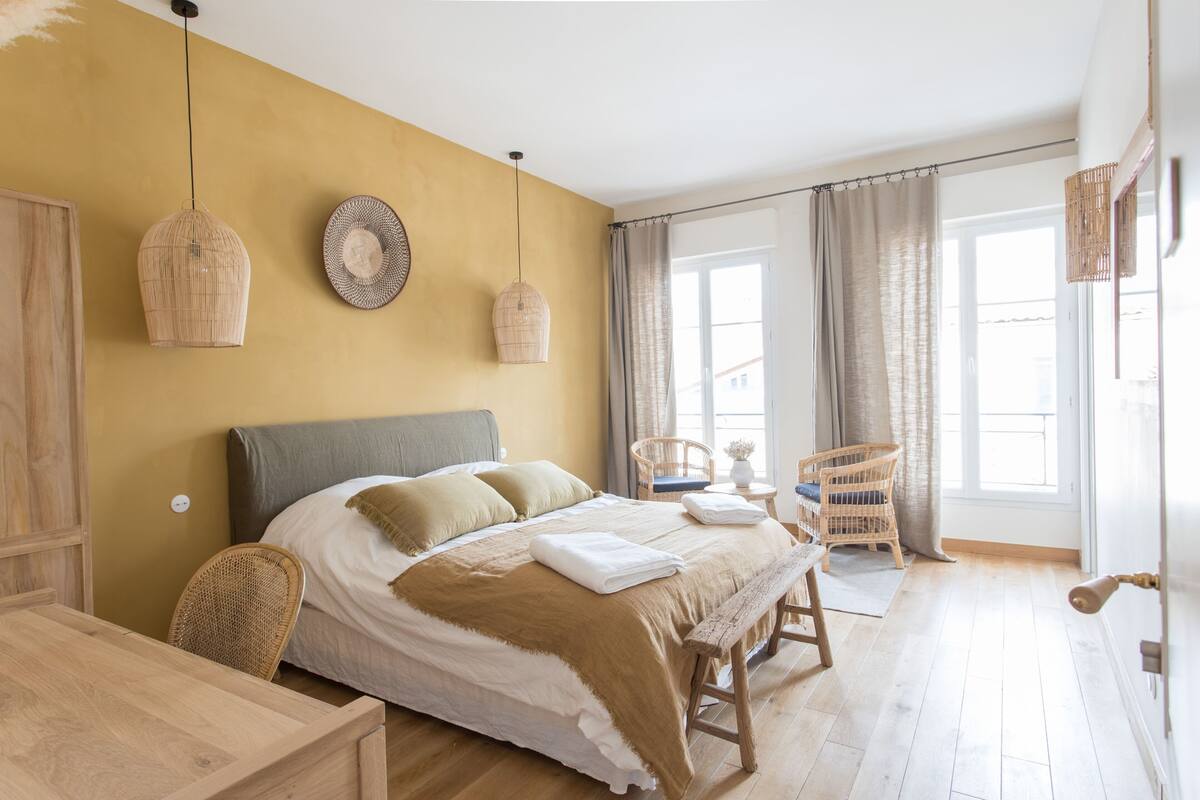 Una camera da letto con un letto, comodini, una sedia e una finestra con tende.