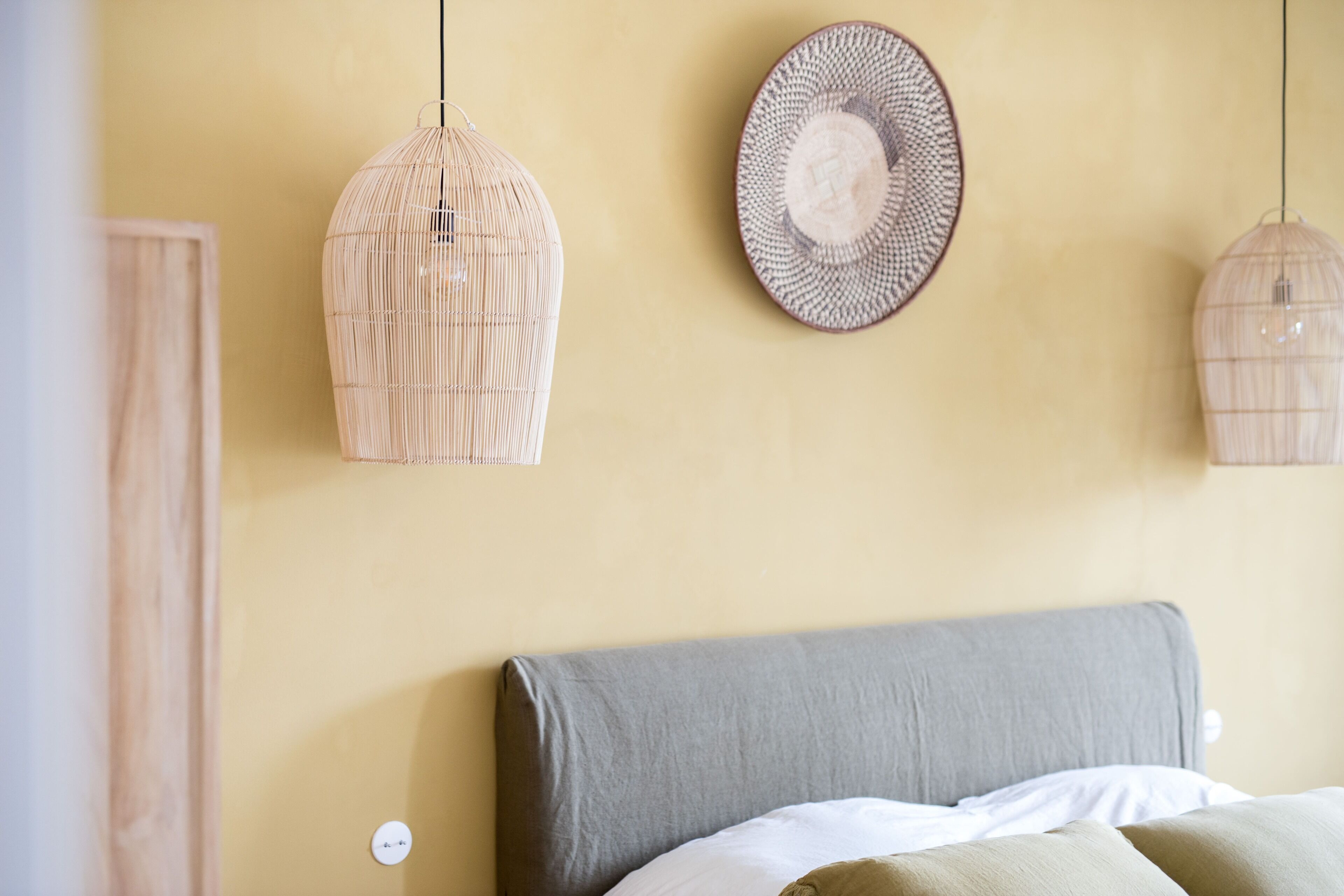 Un dormitorio con una cama, una lámpara de pared y un plato decorativo.