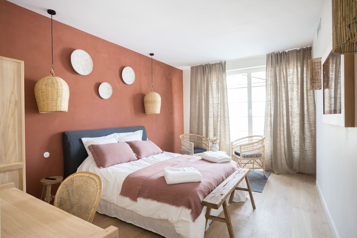 Una camera da letto con un letto, comodini, lampade in vimini e una finestra con tende.
