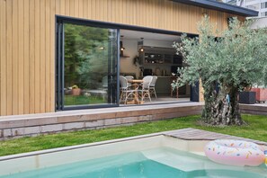 Ein modernes Haus mit einer großen Schiebeglastür, die in einen Essbereich mit Korbmöbeln führt.