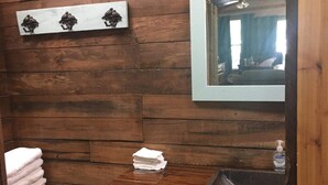 Een houten badkamer met een wastafel, spiegel en handdoekhouder.