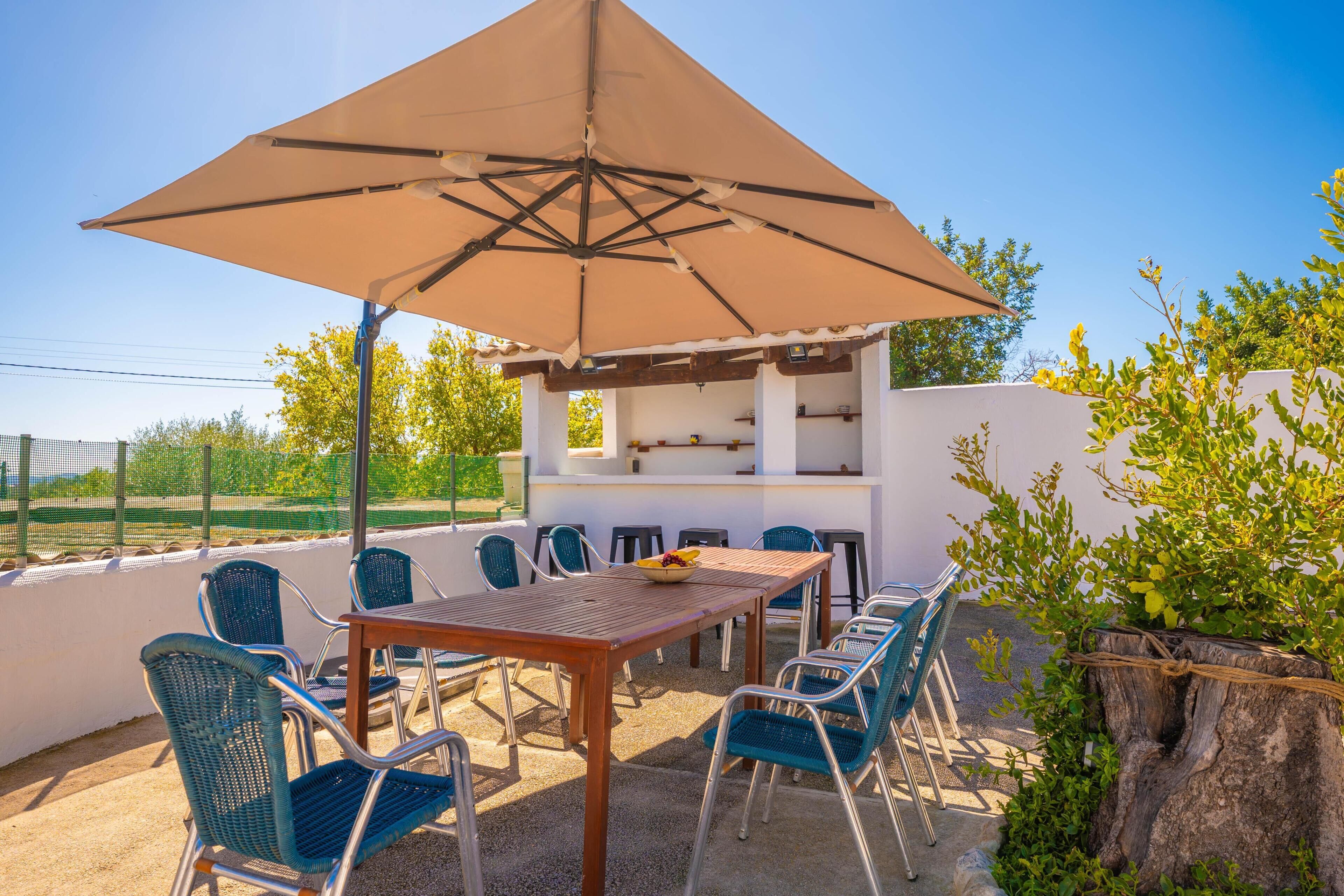 Une terrasse extérieure avec une table, des chaises et un grand parasol.
