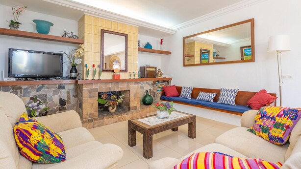 A living room with a fireplace, sofa, television, and a large mirror.