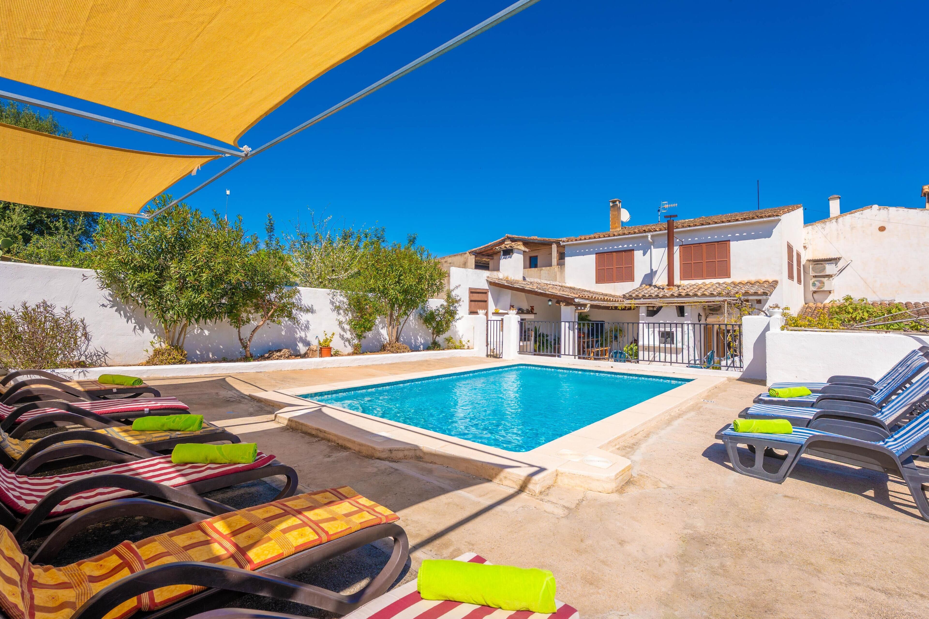 Un espace aménagé au bord de la piscine, avec des chaises longues et une piscine, le tout entouré de bâtiments à l’architecture traditionnelle.