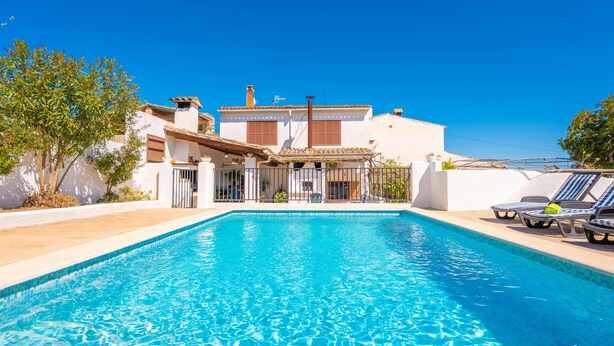 A swimming pool with lounge chairs, a white building with a tiled roof, and a clear blue sky. - CASA CATALINA SAROLA - Village house with a swimming pool in the north of Mallorca (Campanet)