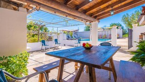 An outdoor patio with a wooden table, chairs, and a bowl of fruit. - CASA CATALINA SAROLA - Village house with a swimming pool in the north of Mallorca (Campanet)