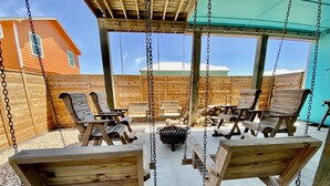 A wooden swing area with benches and a fire pit. - New Listing in Paradise Point Community (Port Aransas)