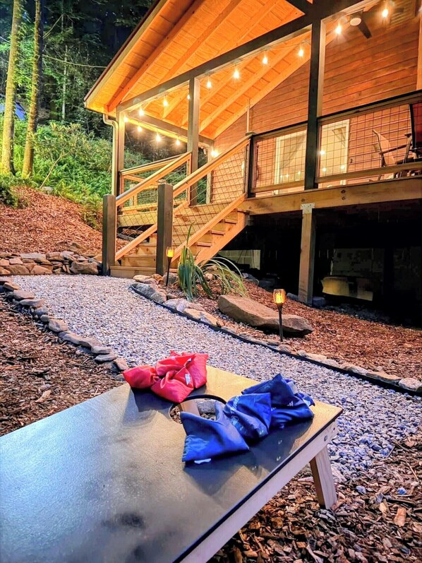 Eine Holzhütte mit überdachter Veranda, einer Treppe und einem Tisch mit Taschen darauf.
