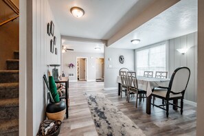 A dining area with a table set for four, a rug, and a staircase leading to another room. - Downtown EUG home Near UO campus & Autzen Stadium (Eugene)